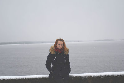 Portrait of woman standing at beach during winter