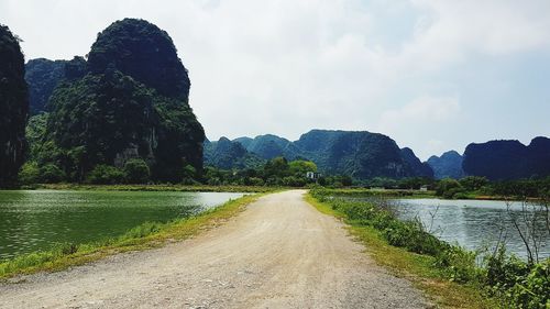 Scenic view of road amidst trees against sky