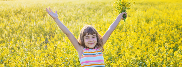 Portrait of cute girl holding flowers while standing in field