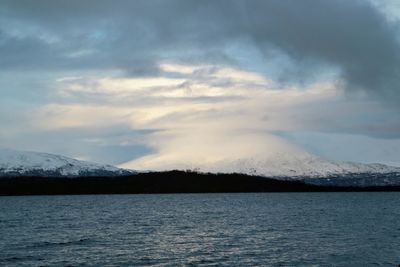 Scenic view of lake by snowcapped mountains against sky
