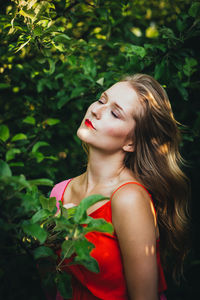 Close-up of young woman with eyes closed standing amidst plants