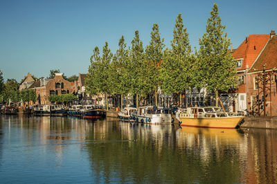 Sailboats moored on river by buildings in city against sky