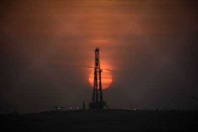Low angle view of silhouette cranes against sky at sunset