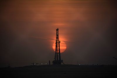 Low angle view of silhouette cranes against sky at sunset