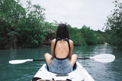 Rear view of woman sitting in boat on lake