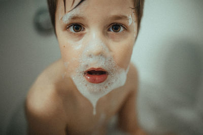 Boy in a bathtub playing with a bubble beard