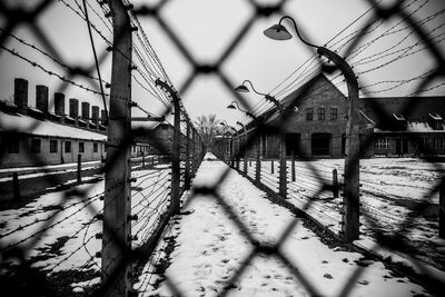 Fence by buildings against sky