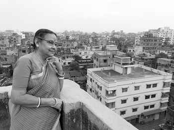 An aged bengali woman enjoying view of urban surroundings from rooftop of a building at howrah india