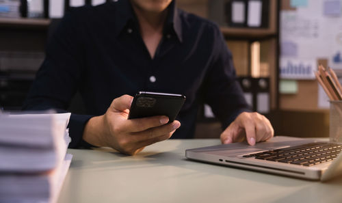 Midsection of woman using laptop on table