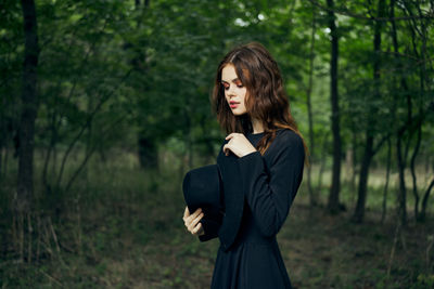 Young woman standing against trees