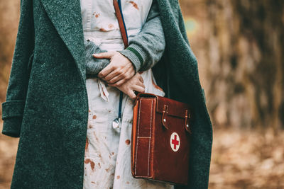 Midsection of woman standing with briefcase and stethoscope