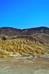 Scenic view of arid landscape against clear blue sky