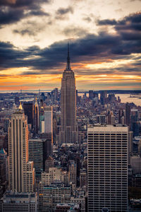 Aerial view of buildings in city against cloudy sky
