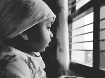 Close-up portrait of cute boy looking through window