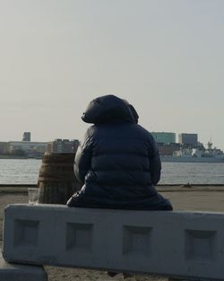 Rear view of man looking at sea against clear sky