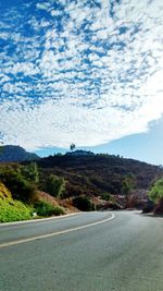 Country road against cloudy sky