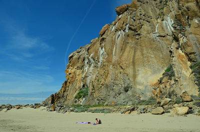 Rock formation on beach against sky