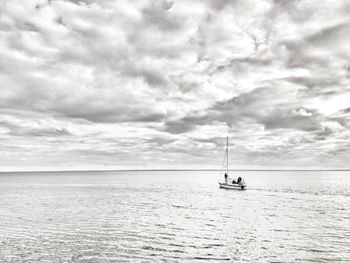 Sailboat sailing in sea against cloudy sky