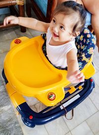 High angle view of cheerful baby girl in walker at home