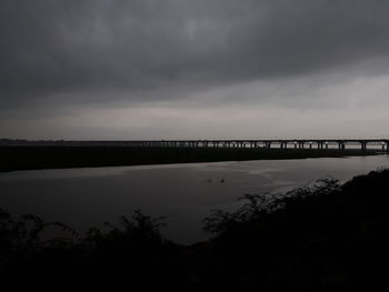 Bridge over silhouette water against sky