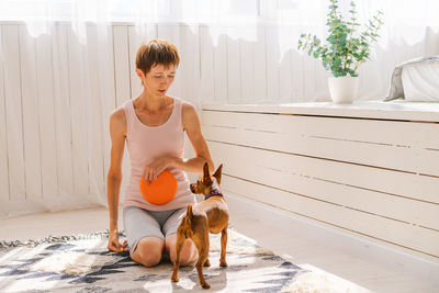 Cute woman practicing yoga with dog breed pygmy pinscher, enjoy and relax