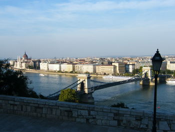 Bridge over river in city against sky