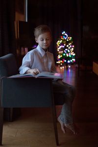 Boy in illuminated christmas tree at night