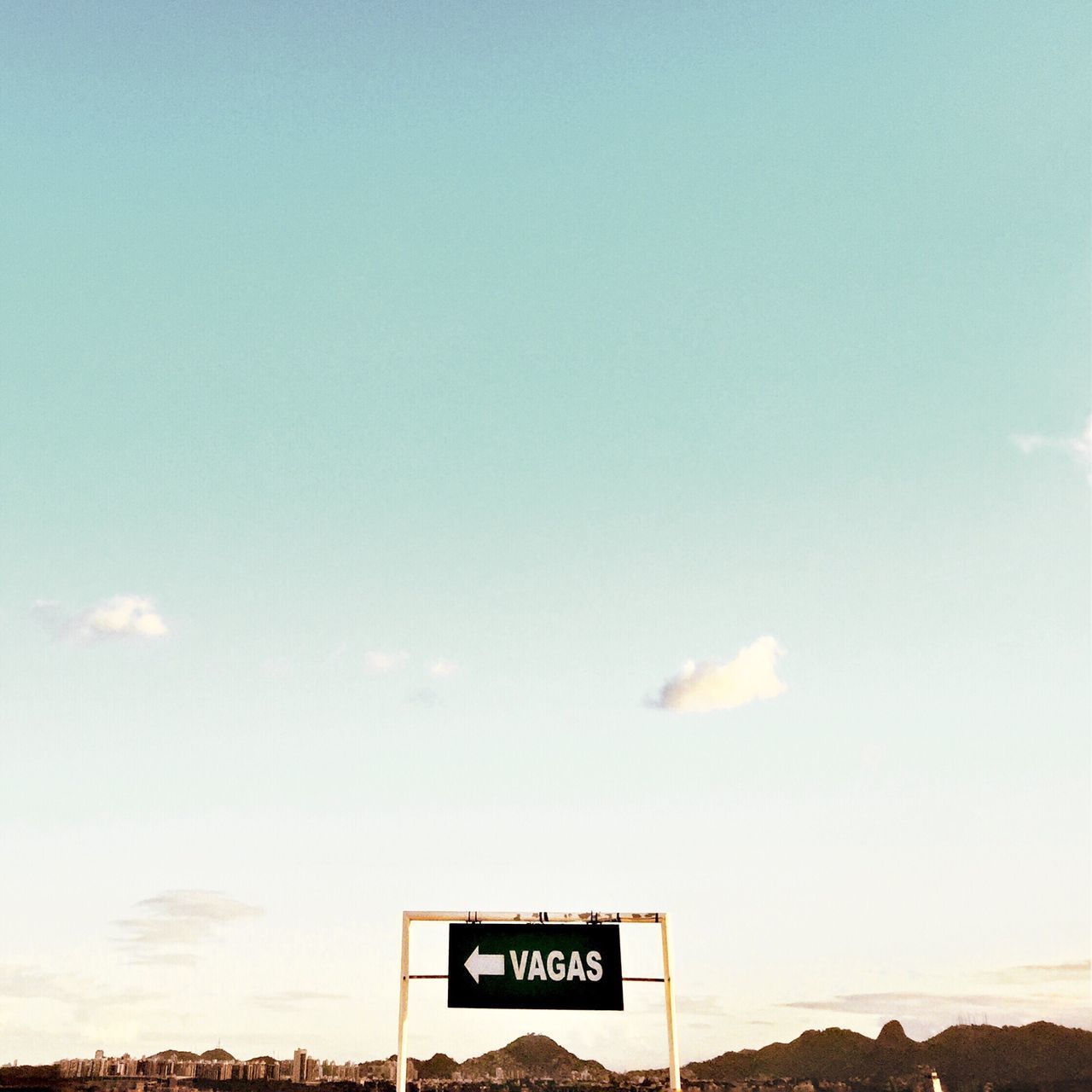 ROAD SIGN BY SIGNBOARD AGAINST SKY