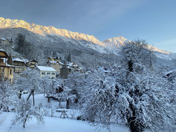 Snow covered houses by mountain against sky