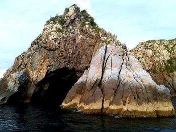 Rock formation in sea against sky