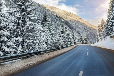 Road by snowcapped mountains during winter