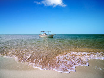 The boat is anchoring at the beautiful beach on a sunny day.