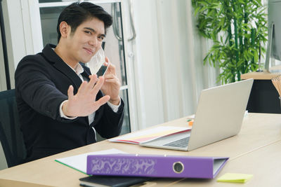 Young man using mobile phone at table