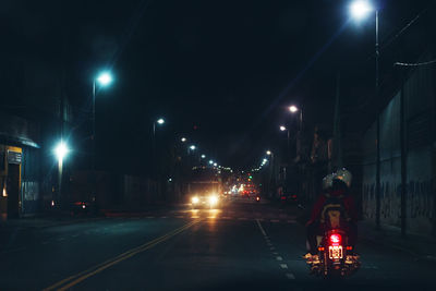 Cars on illuminated city street at night