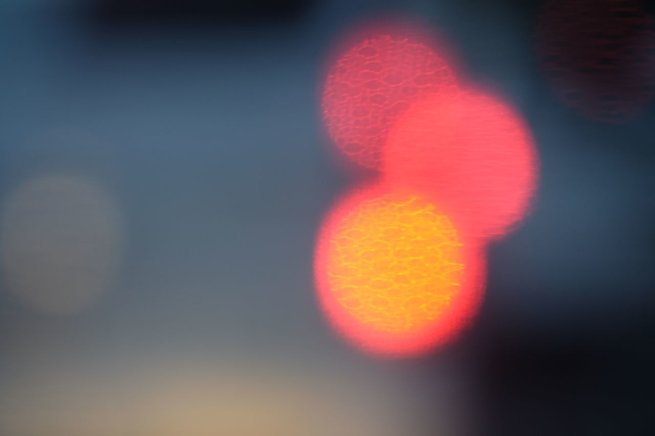 DEFOCUSED IMAGE OF ILLUMINATED LIGHTS AGAINST ORANGE SKY