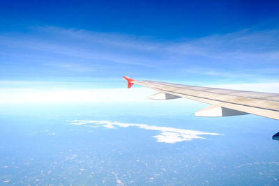 Airplane wing over clouds against blue sky