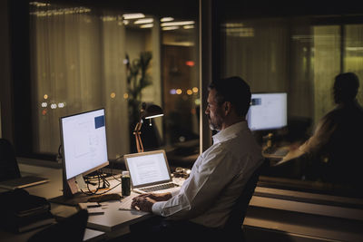 Businessman typing on computer keyboard while working in office at night