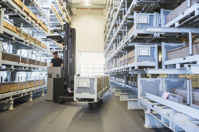 Worker with forklift in factory warehouse