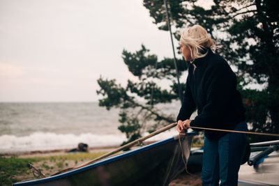 Young woman tying boat at beach