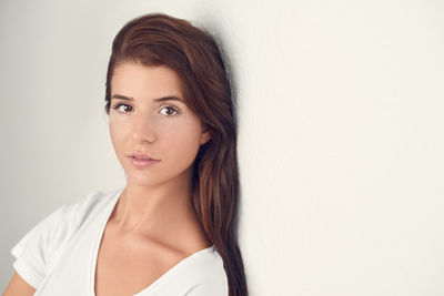 Portrait of smiling young woman against white wall