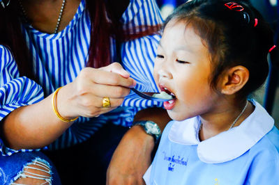 Midsection of mother feeding daughter