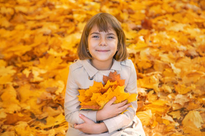 Portrait of woman standing amidst yellow autumn leaves