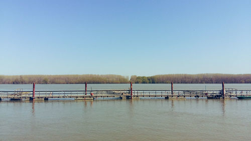 Pier over lake against clear blue sky