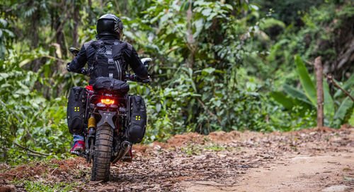 Woman riding her scrambler type motorcycle through forrest