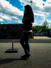 Silhouette of woman standing against cloudy sky