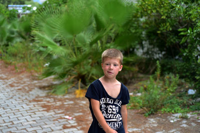 Boy looking away against plants