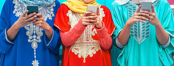 Midsection of women in traditional clothing using phones