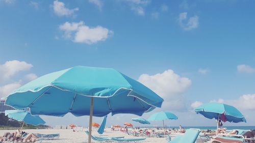 Beach umbrellas by sea against sky