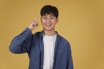 Portrait of smiling boy standing against yellow background