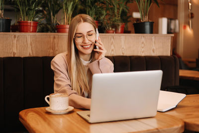 A millennial business woman works and studies online using a mobile phone and technology in a cafe